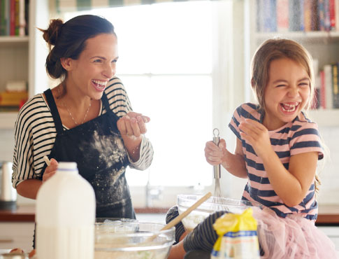 A mom and young girl baking in a kitchen